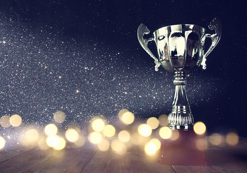 silver trophy on dark sparkly background with bokeh