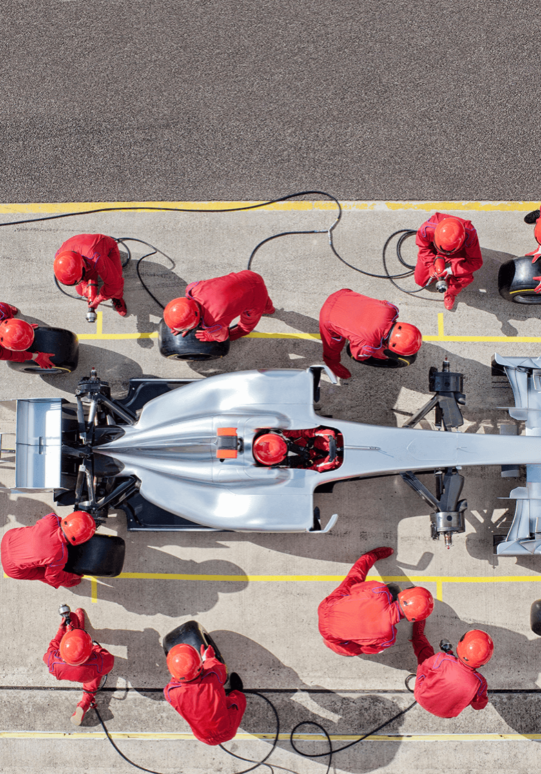 aerial shot of a team in red uniforms working on a fast car